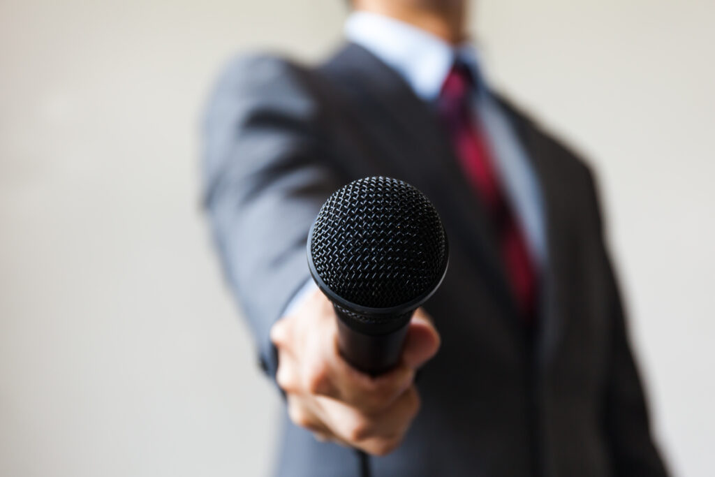 Man in business suit holding a microphone speak voice