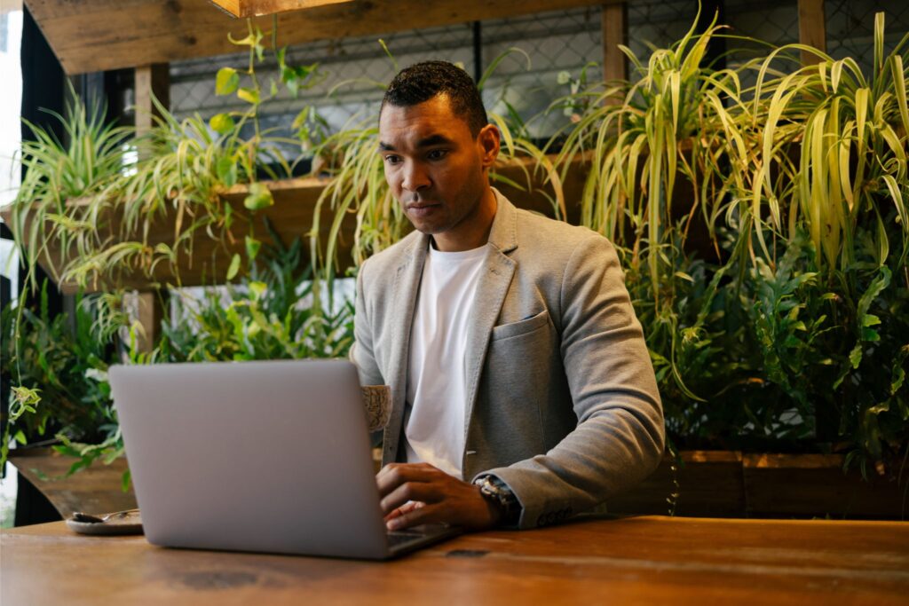 African-American man taking a professional development assessment on his laptop in the cafeteria.