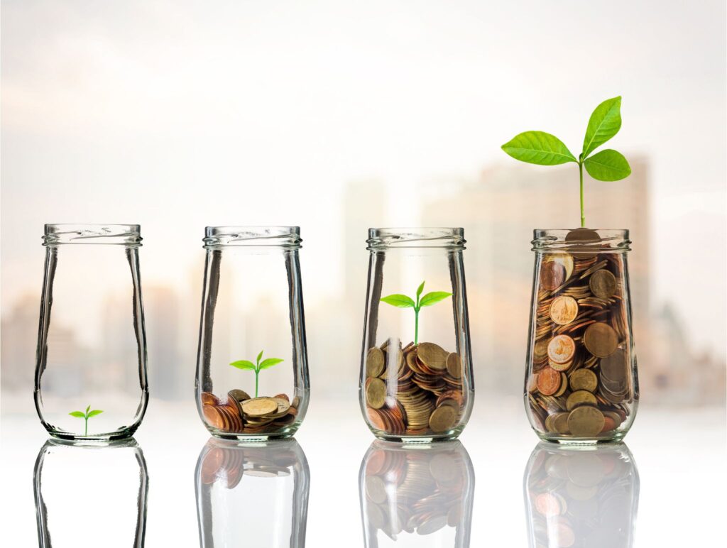 Gold coins and seed growth in clear bottles on a cityscape background representing growth.