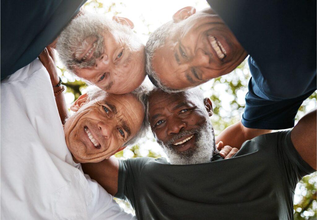 Older men huddling together outdoors looking down at the camera from above