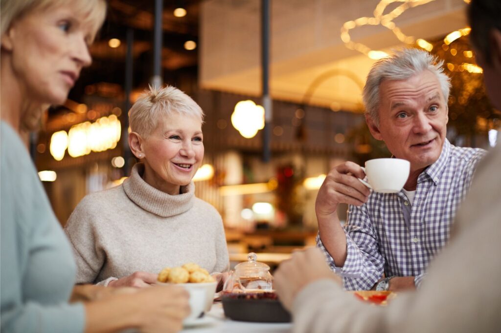 Positive male and female seniors drinking tea together