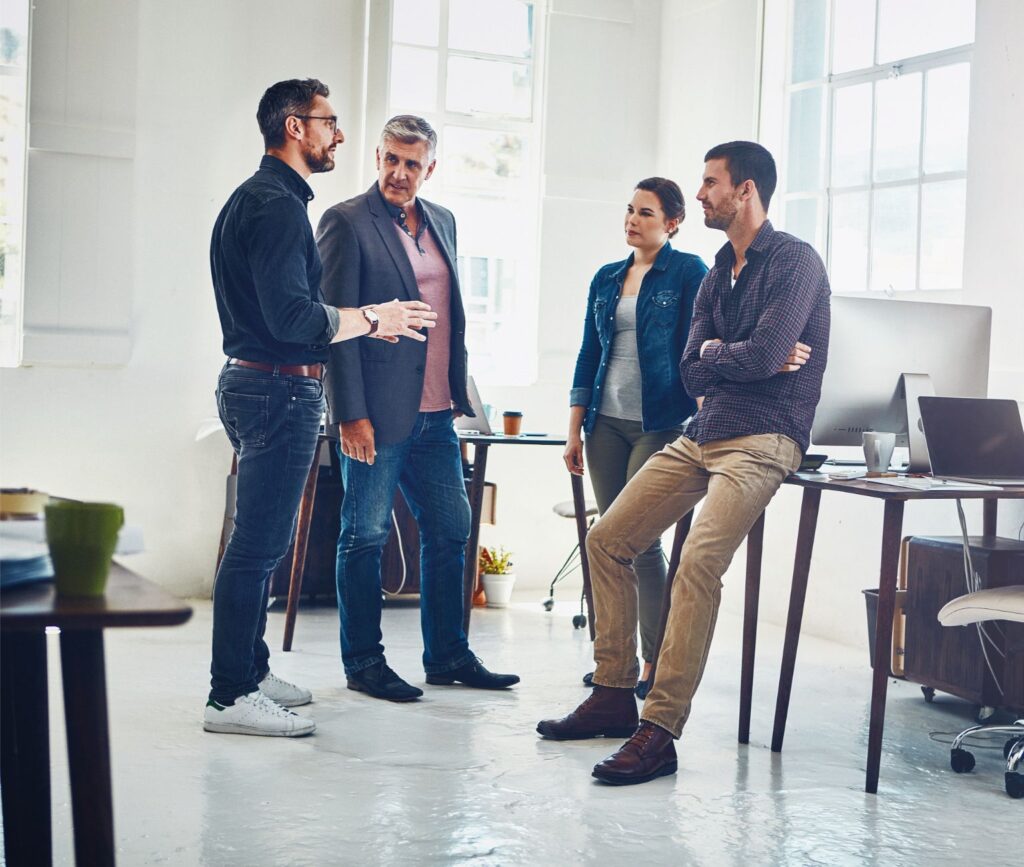 Leader communicating to his team huddled at their desks in an open office environment