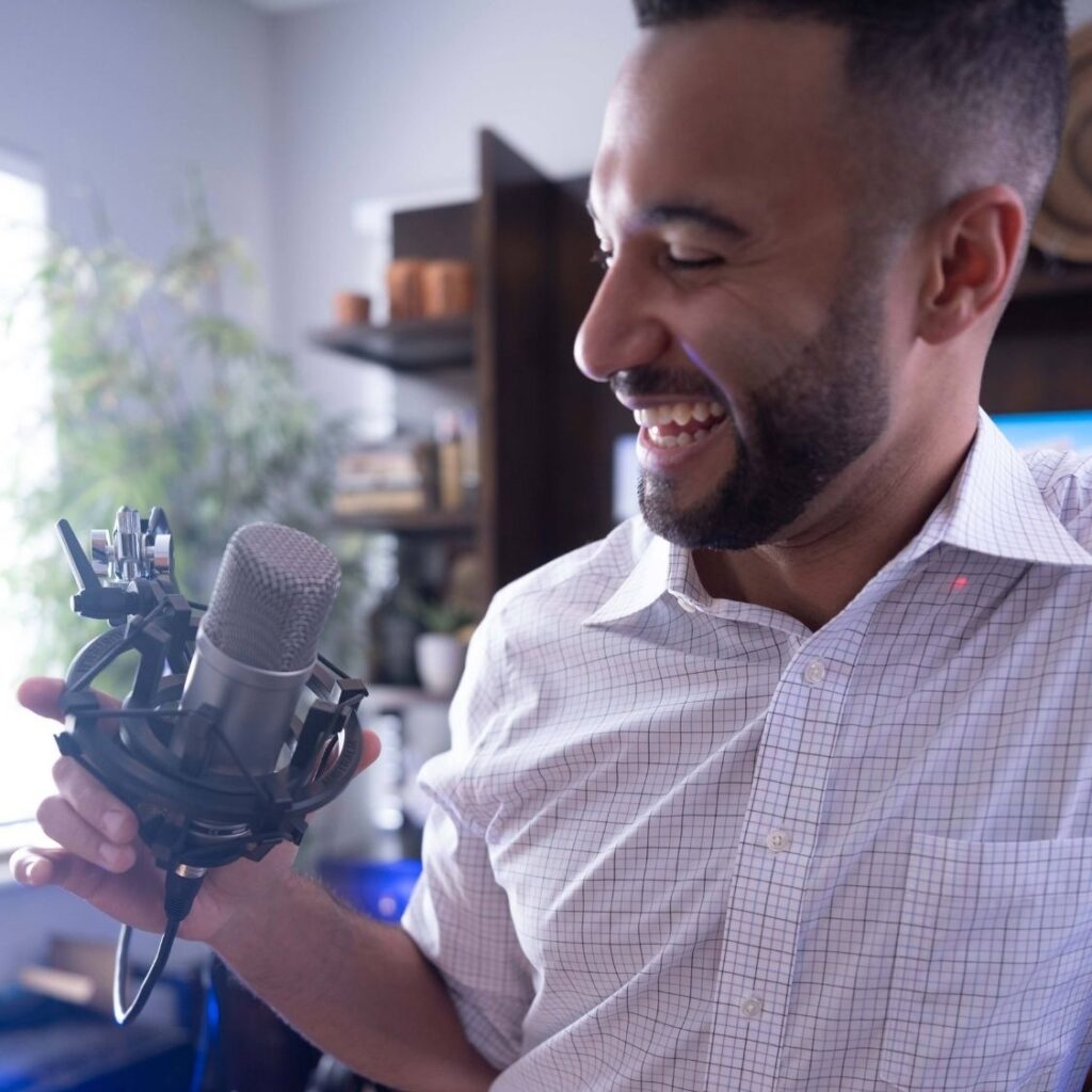 the present professional host, John Marshall, looking at his microphone smiling